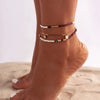A set of bohemian sequin rice bead anklets worn on a person's ankle.