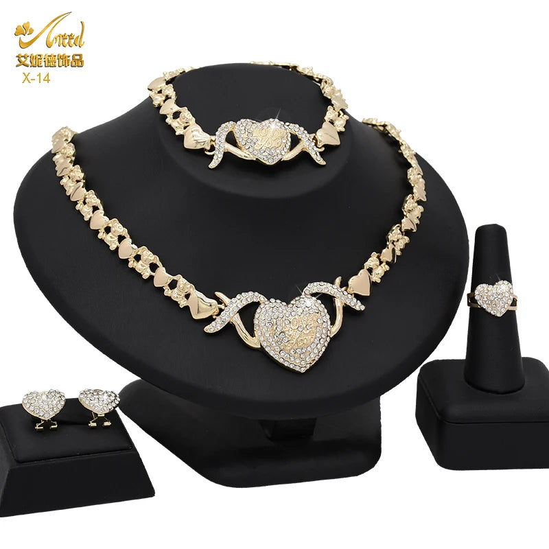 A set of 18K gold heart crystal jewelry including a necklace and earrings displayed on a black stand.