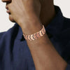 A close-up of a man's wrist wearing a rose gold copper magnetic bracelet on his forearm.