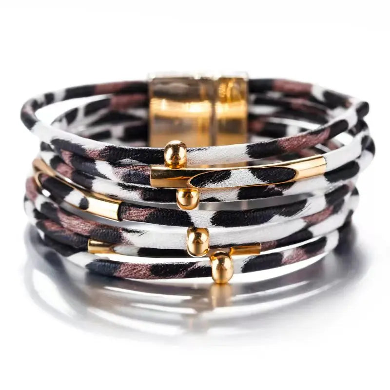 Une pile de bracelets à enrouler en cuir léopard bohème avec des accents dorés.