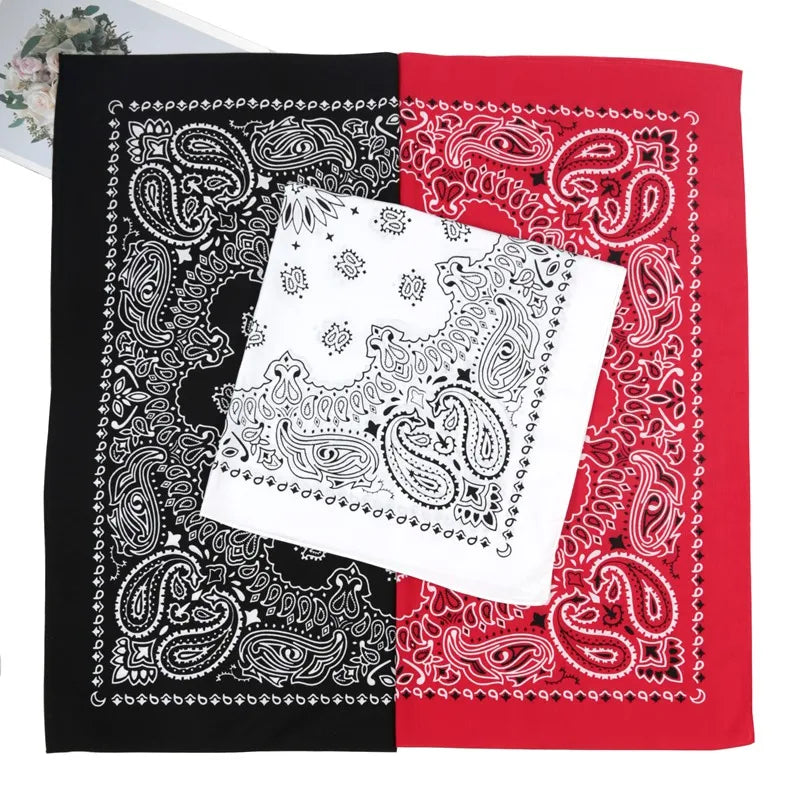 A folded bandana scarf featuring black and red paisley patterns on a white background.