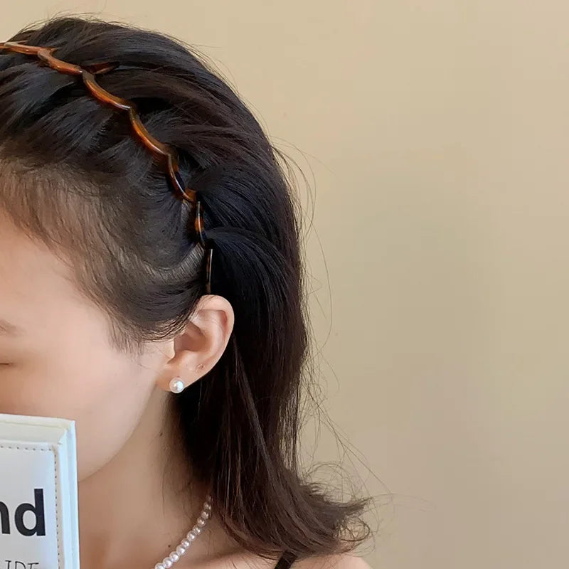 A close-up of a woman wearing a brown resin wave toothed headband in her dark hair.