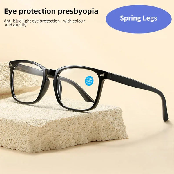 A pair of black, rectangular anti-blue light eyeglasses resting on a textured white surface.