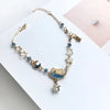 A sterling silver double heart charm bracelet featuring blue stones and a gold cat pendant.