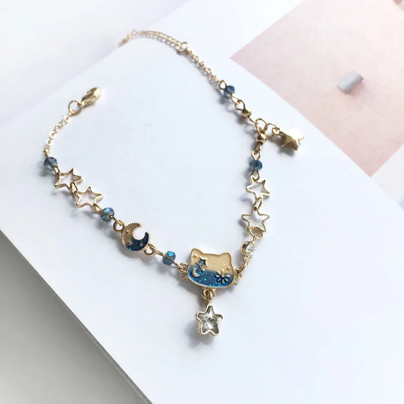 A sterling silver double heart charm bracelet featuring blue stones and a gold cat pendant.