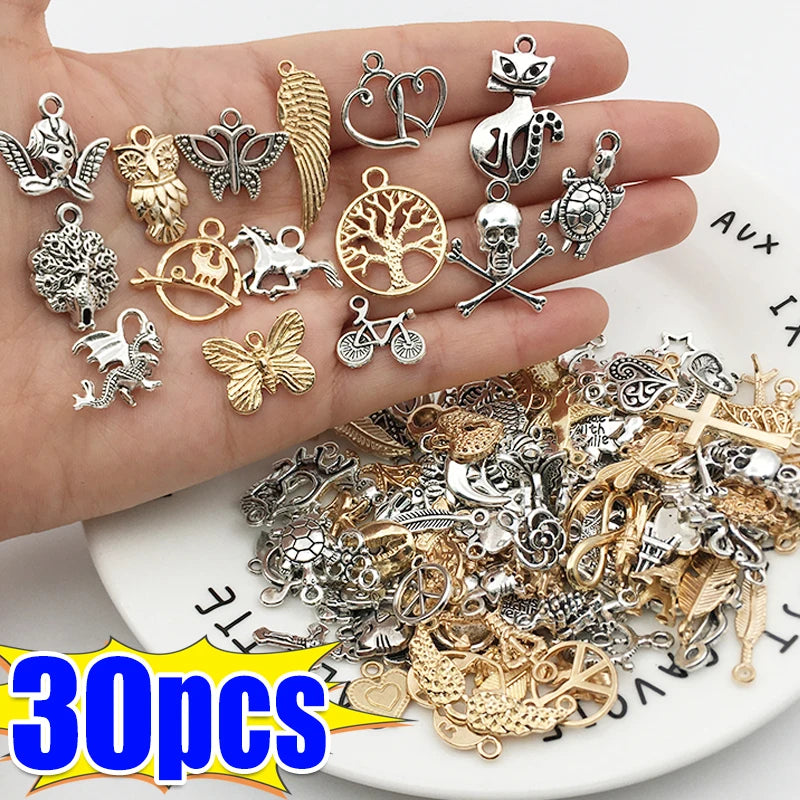 Eine Hand hält verschiedene silberne und goldene tibetische Anhänger für DIY-Schmuck.