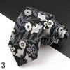 Dunkelgraues und weißes Blumen-Paisley-Männer-Anzugband auf schwarzer Oberfläche.