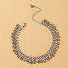 A close-up of an elegant bell foot chain anklet made of silver-toned metal and clear stones.