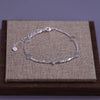 Sterling silver double heart charm bracelet displayed on a brown wooden box with a beige fabric background