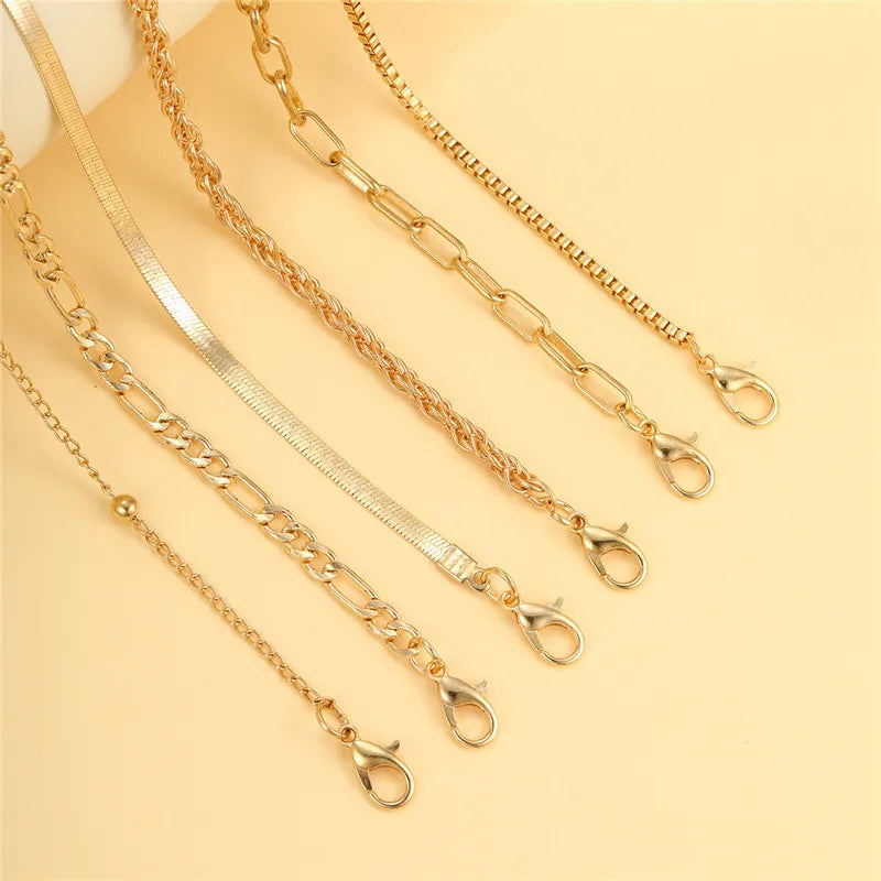 Ein Set zierlicher goldener geometrischer Fußkettchen für Damen auf hellem Hintergrund.