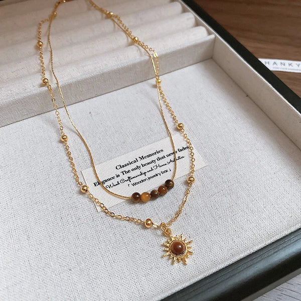 Goldkette mit Tigerauge-Sonnenblumen-Anhänger in weißer Schachtel.