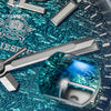 A close-up of a diving quartz wristwatch with luminous features resting on a textured blue background.