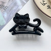 A black cat hair clip featuring a bow, displayed on a white surface.