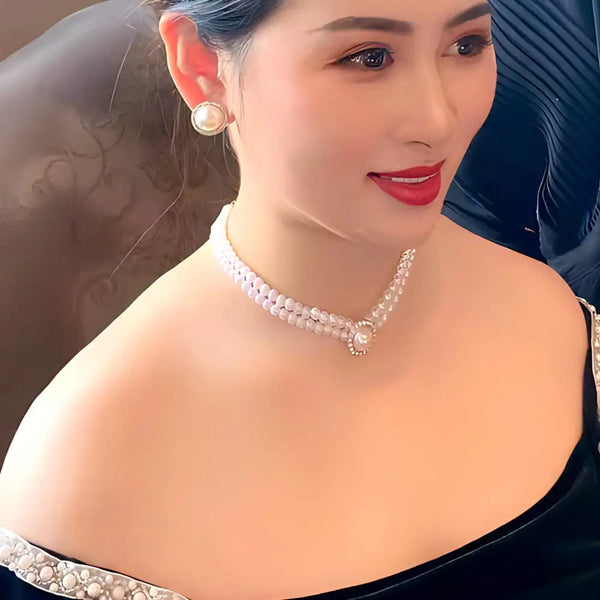 Eine Frau mit einem eleganten Perlen- und Ohrschmuck und rotem Lippenstift.