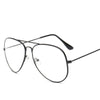 Lunettes avec monture dorée rétro et branches métalliques fines sur fond blanc