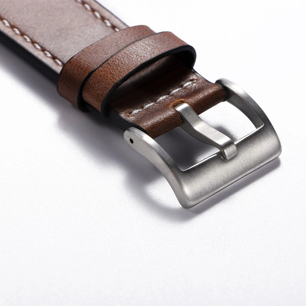 A close-up of a brown calfskin leather watch strap with a silver buckle.