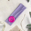 Purple stretch hairband with a pink wind dot detail on a white background.