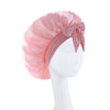 A pink satin wide-brimmed hair wrap headscarf tied with a bow displayed on a mannequin.