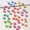 A collection of colorful mini flower hair clips scattered on a white background.