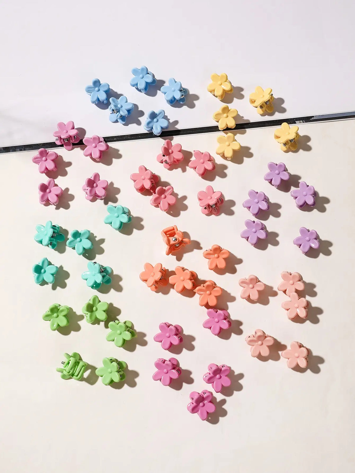 A collection of colorful mini flower hair clips scattered on a white background.
