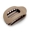 A matte beige oval hair claw clip with a leopard print design shown from above.