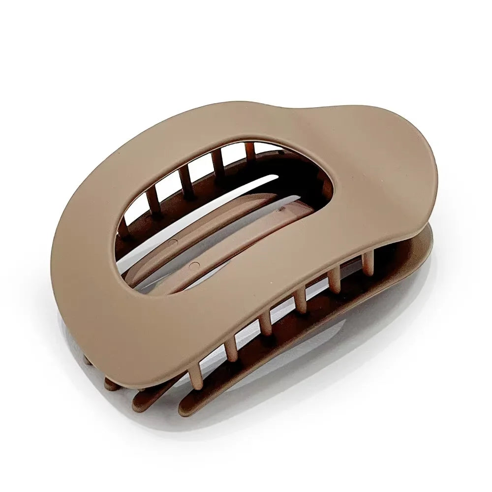 A matte beige oval hair claw clip with a leopard print design shown from above.