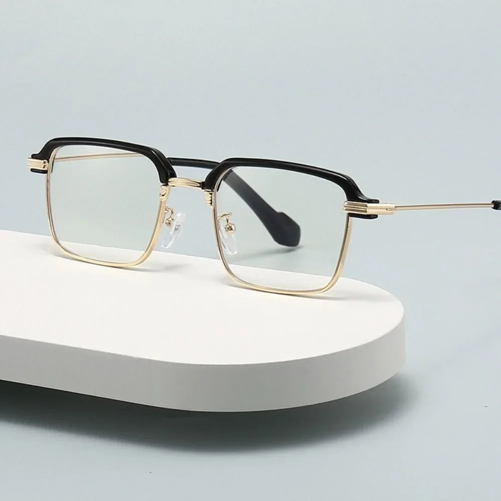 Une paire de lunettes de lecture photochromiques noir et or posée sur une surface blanche.