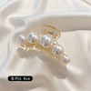 A delicate gold-toned hair claw featuring several round simulated pearls.