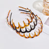 A set of textured hair bands in shades of amber and black arranged on a white surface.