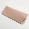 A light pink PU leather glasses case is shown lying flat on a white background.