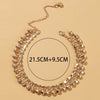 A gold-toned bell foot chain anklet is displayed on a neutral background, showing its circular design and dimensions.