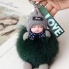 A cute cartoon plush doll with a gray knitted hat and dark green fur, attached to a keychain.