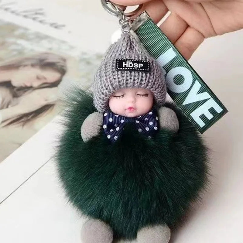 A cute cartoon plush doll with a gray knitted hat and dark green fur, attached to a keychain.