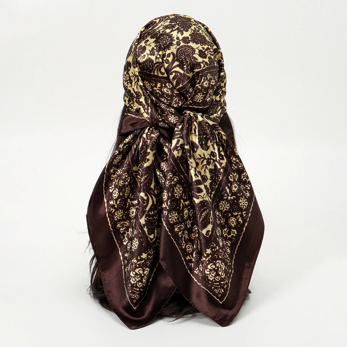 A dark brown silk scarf with a leopard print pattern tied in a knot.