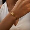 A close-up of a person's wrist wearing a gold stainless steel bracelet engraved with the word LIBRA.