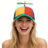 A young woman smiling while wearing a funny multicolor propeller hat.