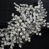 A delicate bridal headpiece featuring white pearls and clear rhinestones arranged in a floral design.