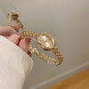 A hand is holding a gold-toned quartz fashion wristwatch with a linked bracelet.