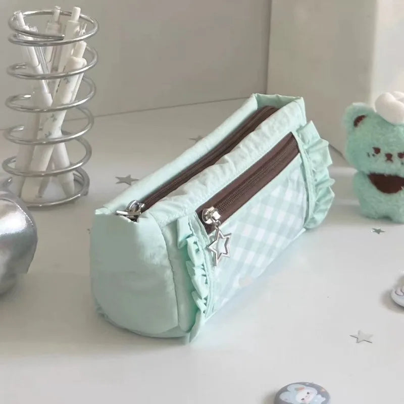 A light mint green lace pencil case with a zipper and star embellishments is displayed on a white surface.