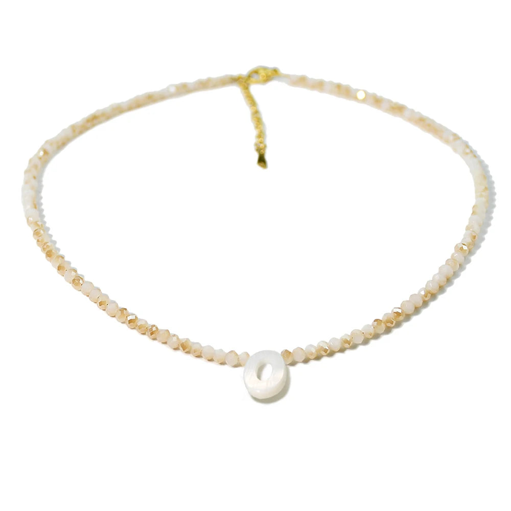 A delicate necklace made of mother of pearl beads with crystal accents and a gold-colored cord.