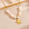 Gold chain necklace featuring pink and white floral beads and a gold starfish heart pendant