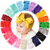 A colorful arrangement of soft baby headbands and chunky hair bows in various pastel and vibrant colors.
