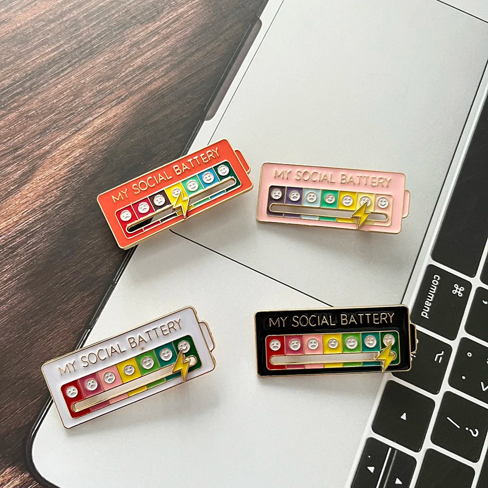 Drei schiebbare Stimmungspunktepins in rot, pink und schwarz auf einer weißen Laptop-Tastatur.