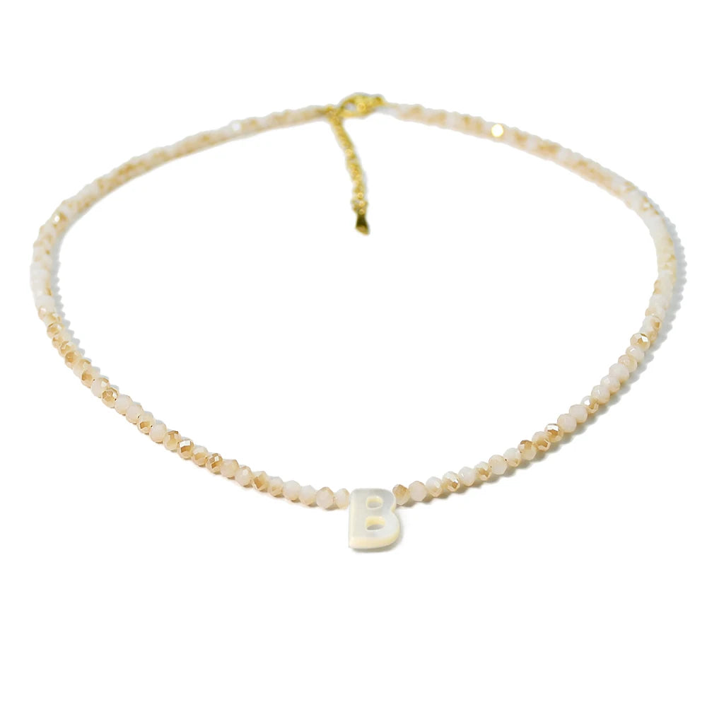 A delicate necklace featuring mother of pearl beads and crystal accents with a letter initial charm.