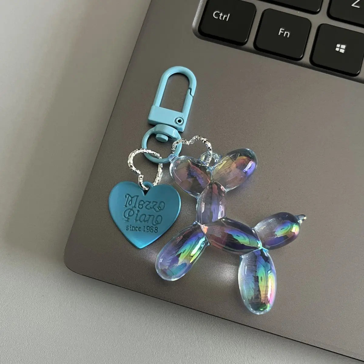 A teal resin animal dog keychain with a heart shape and a silver clasp resting on a laptop keyboard.