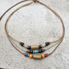 A set of boho vintage wood and stone bead necklaces laid on a gray concrete surface.