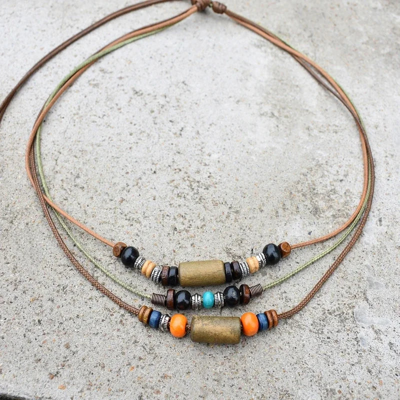 A set of boho vintage wood and stone bead necklaces laid on a gray concrete surface.