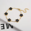 Pulsera de acero inoxidable chapada en oro con adornos de flores negras en una cadena dorada.