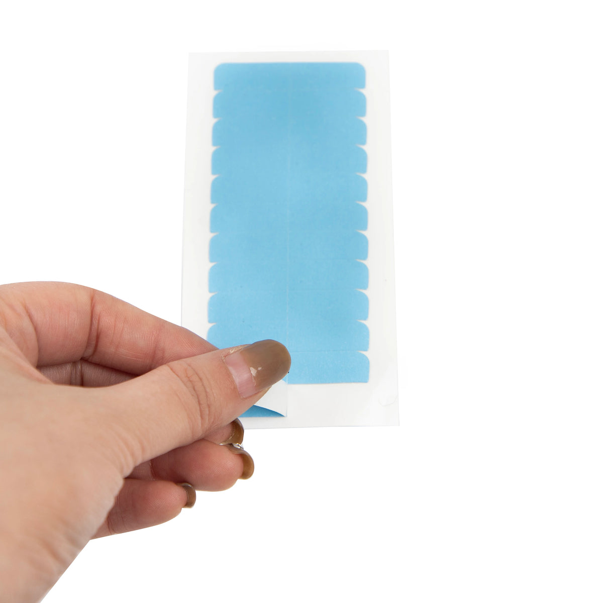 A hand holds a clear plastic tape with blue, serrated edges, used for hair extension adhesive.
