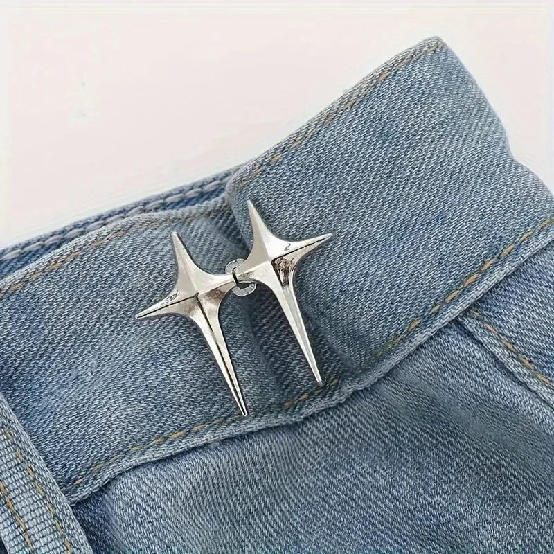 A pair of silver star-shaped decorative waist buckle buttons sewn onto a denim fabric.